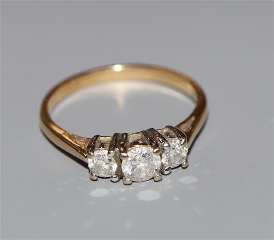 A modern 18ct gold and three stone diamond ring, with IGI report stating the total diamond weight to be 0.75cts, size Q.